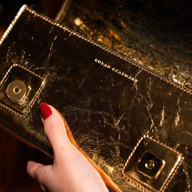 Minimalist designer leather clutch featuring a hidden magnetic closure and embossed logo.